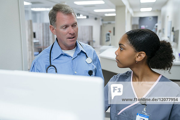 Arzt und Krankenschwester im Gespräch am Computer
