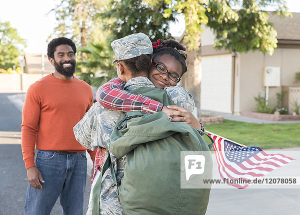 Mann beobachtet schwarze Soldatin  die ihre Tochter umarmt