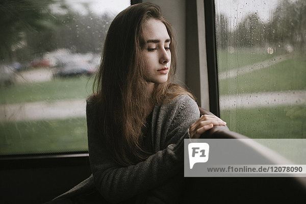Nachdenkliche kaukasische Frau sitzt im Bus im Regen