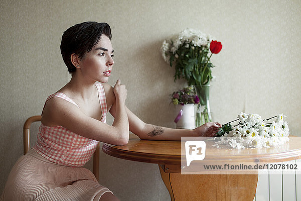 Pensive Caucasian woman sitting at table with flowers