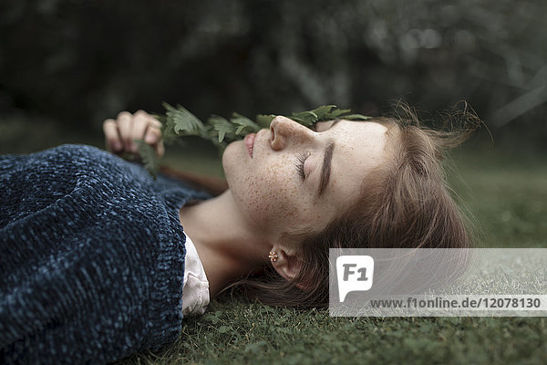 Caucasian girl with freckles laying in grass