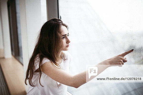 Caucasian woman pointing at rain on window
