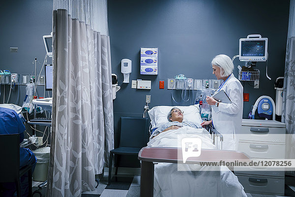 Arzt spricht mit Patient im Krankenhausbett