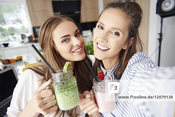 Selfie of happy friends holding smoothies