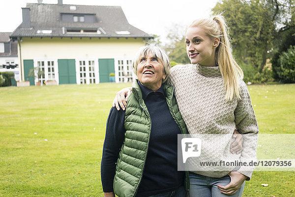 Lächelnde junge Frau  die mit ihrer Großmutter im Garten steht.