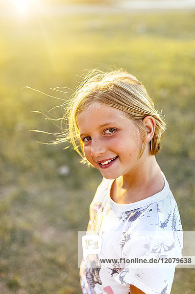 Porträt eines lächelnden blonden Mädchens im Gegenlicht