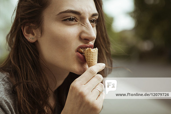 Junge Frau beim Essen einer Eistüte im Freien