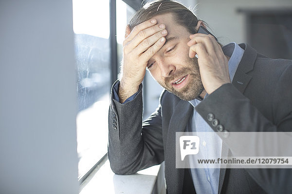 Frustrated businessman in office talking on the phone