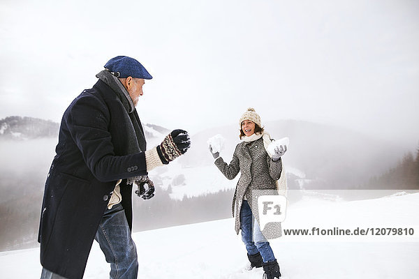 Senior couple having a snowball fight in the snow