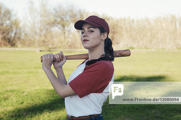 Portrait einer jungen Frau mit Baseballschläger im Park