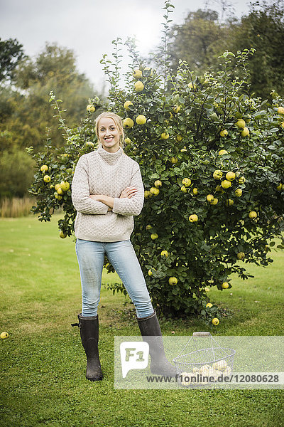 Portrait of smiling young woman at quince tree in garden