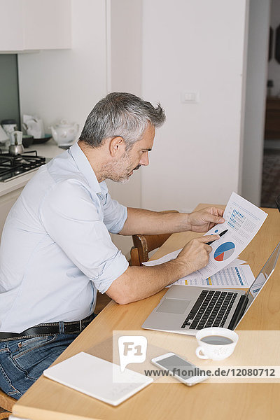 Mann analysiert Daten und nutzt Laptop im Home-Office