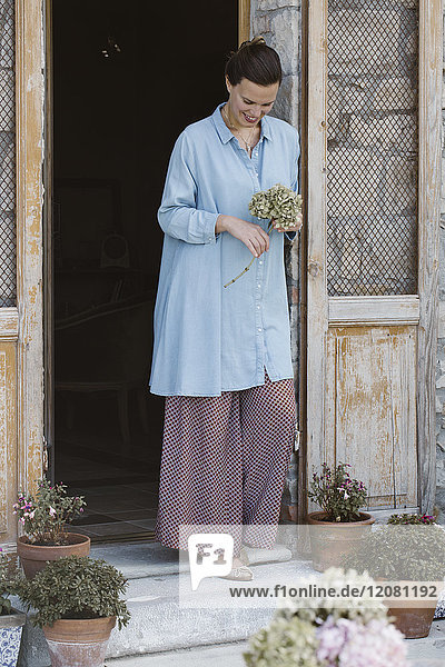 Italien  lachende Frau mit Blumenkopf von Hortensia auf der Terrasse