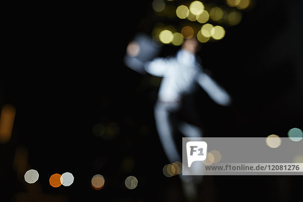Silhouette des verschwommenen tanzenden Mannes bei Nacht