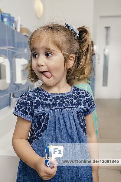Porträt eines Mädchens mit Zahnbürste im Bad eines Kindergartens