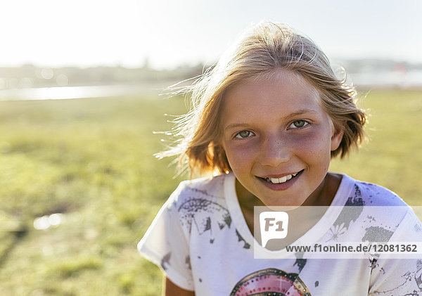 Porträt eines lächelnden blonden Mädchens bei Sonnenlicht