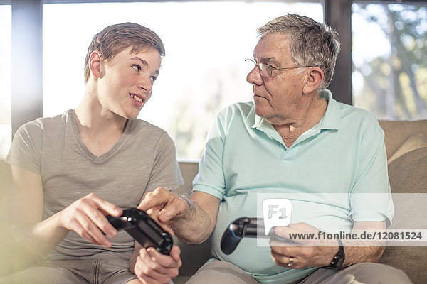Großvater und Enkel spielen Videospiel auf der Couch zu Hause
