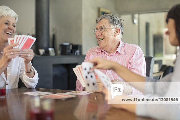 Senior couple playing cards with daughter at home