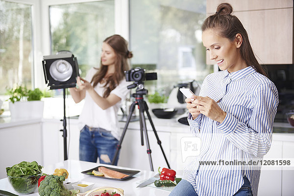 Frau benutzt Smartphone vor dem Kochen