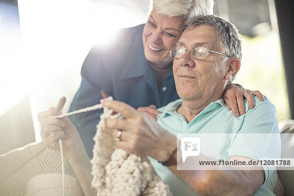 Glückliches Seniorenpaar auf der Couch zu Hause stricken