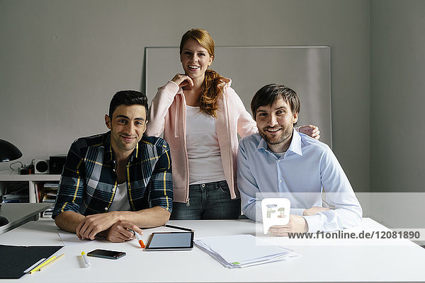 Portrait of smiling colleagues at desk in office