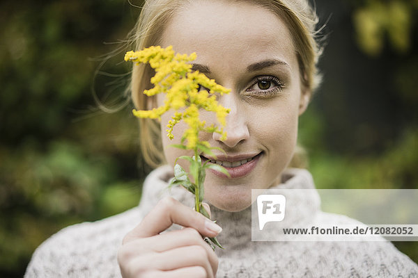 Portrait of smiling young woman holding wild flower