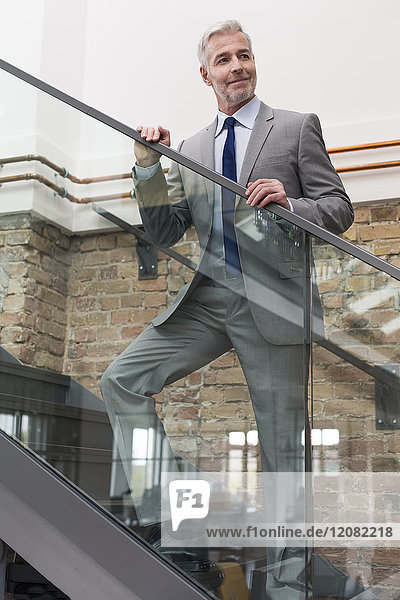 Ausgereifter Geschäftsmann im modernen Büro auf einer Treppe stehend