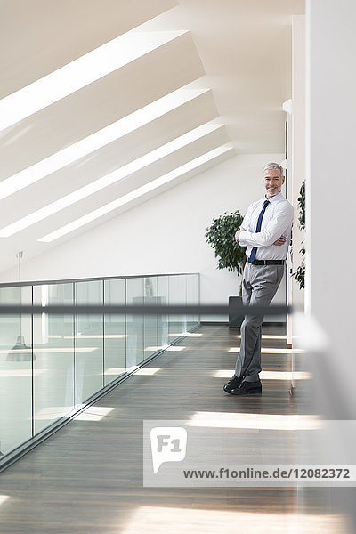 Serene businessman standing in office  smiling