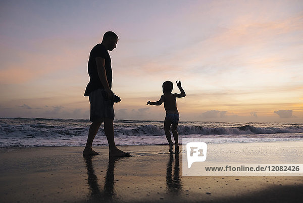 Indonesien  Bali  Vater und Sohn am Strand bei Sonnenuntergang