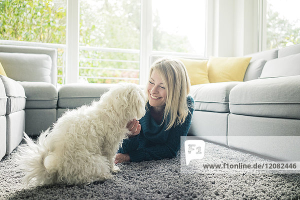 Lächelnde Frau streichelt ihren Hund im Wohnzimmer