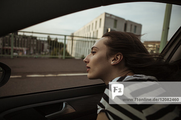 Young woman leaning out of car window