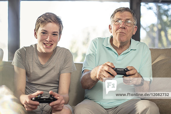 Grandfather and grandson playing video game on couch at home