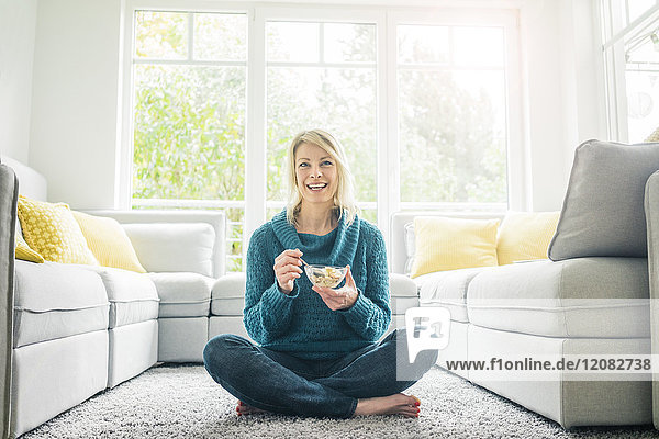 Porträt einer glücklichen Frau beim Müsliessen im Wohnzimmer