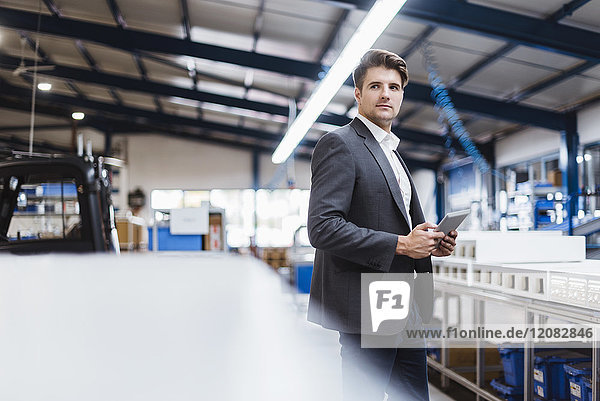 Young manager standing in shop floor with digital tablet  portrait