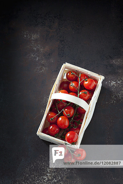 Schienenkorb mit Kirschtomaten auf dunklem Grund