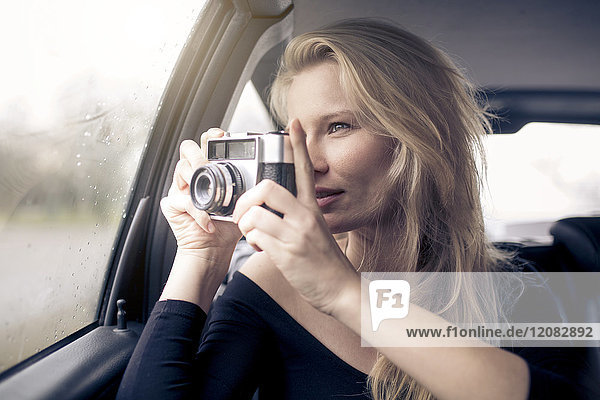 Frau im Auto sitzend fotografiert mit Kamera