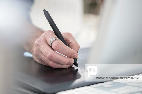 Beschnittene Ansicht eines Mannes  der mit einem digitalen Stift schreibt