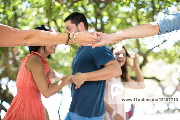 Erwachsene Freunde halten sich an den Händen und tanzen gemeinsam auf einer Strandparty