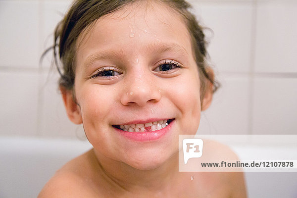 Porträt eines Mädchens mit fehlendem Zahn im Bad  lächelnd in die Kamera blickend