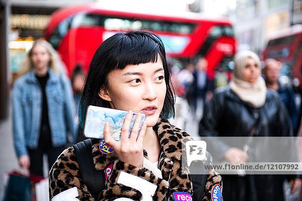 Stilvolle junge Frau schlendert auf der Straße und telefoniert mit ihrem Smartphone  London  UK