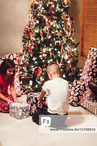Brother and sister unwrapping gifts on Christmas day