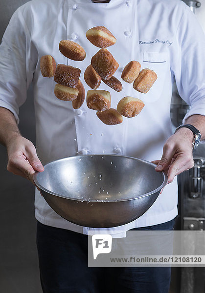 Cropped view of chef tossing doughnuts and sugar in mixing bowl