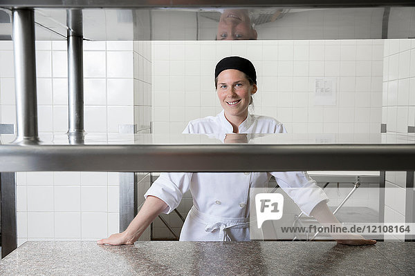 Porträt eines Küchenchefs in einer Großküche  der lächelnd in die Kamera schaut