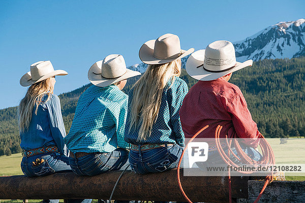 Rückansicht von Cowboys und Cowgirls am Zaun  wegschauend  Enterprise  Oregon  Vereinigte Staaten  Nordamerika