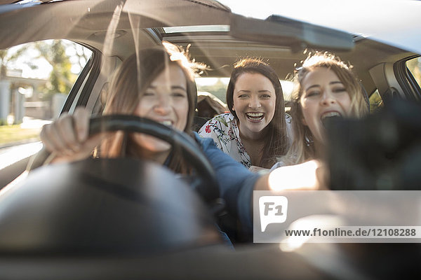 Drei junge Frauen im Auto  Fahrer stellt Navi am Fenster ein