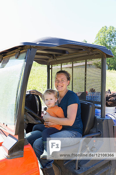 Porträt einer Bäuerin und einer Kleinkind-Tochter im Lastwagen auf freilaufendem Biobauernhof