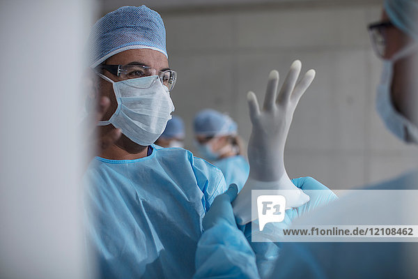 Chirurgen  die sich auf die Operation vorbereiten  Latexhandschuhe anziehen