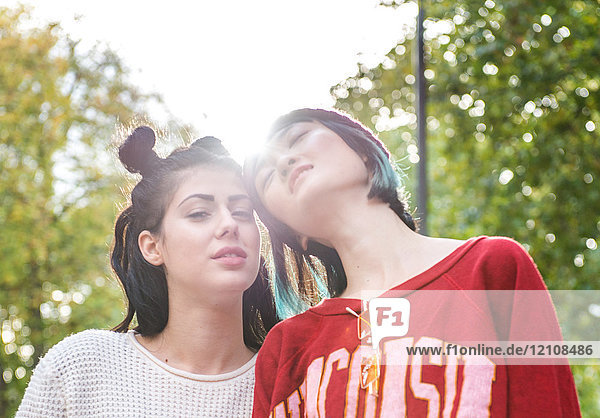Portrait of two young stylish women in city park