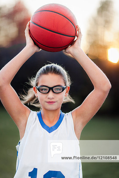 Porträt eines Mädchens mit Sportbrille  das Basketball hält