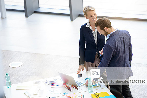 Businesswoman and man having discussion at office table